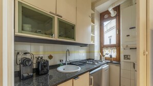Una cocina compacta con horno integrado, un lavamanos y un ventanal sobre el lavamanos.