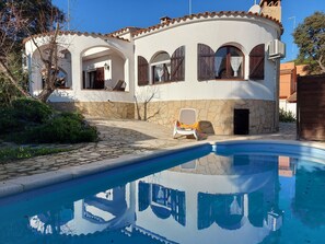 Une maison avec une piscine, des murs en pierre et des fenêtres en arc de cercle.