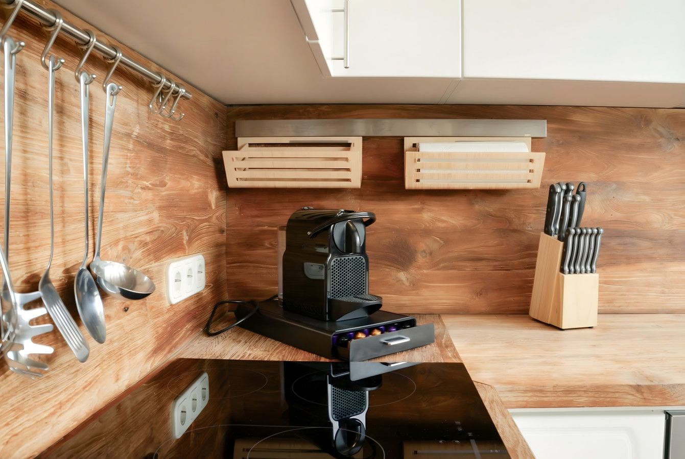 Eine kleine Küche mit einer Kaffeemaschine, Geschirr, das an der Wand hängt, und einem Messerblock.