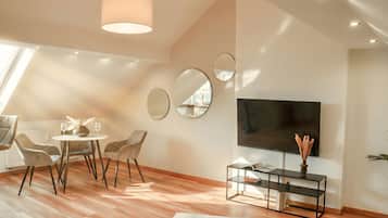 Ein modernes Wohnzimmer mit Essbereich, einem Flachbildfernseher und einem großen Fenster.