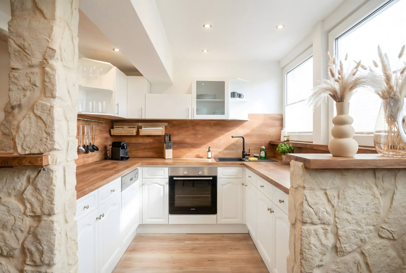 Eine moderne Küche mit weißen Schränken, einer Holz Arbeitsplatte und einem eingebauten Backofen.