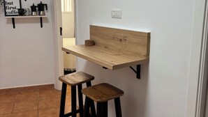 A small kitchen with a wooden countertop, two stools, a clock, and shelves with kitchen items. - The Vistamar Suite 154 (Tacoronte)