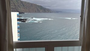 A coastal view from a window, including a rocky shoreline and a distant cityscape. - The Vistamar Suite 154 (Tacoronte)