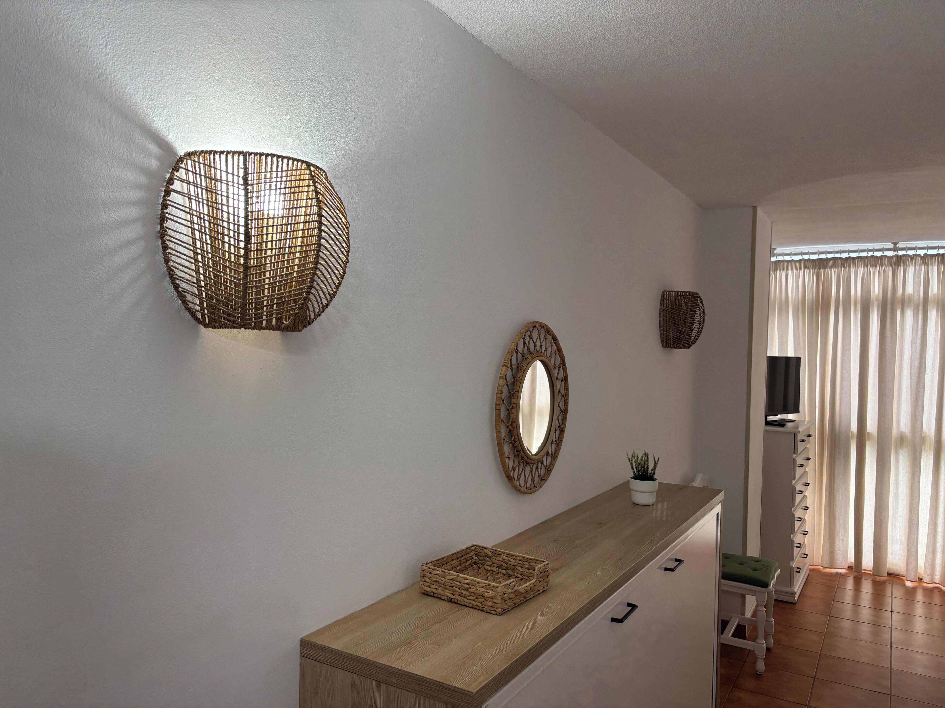Een modern interieur met een houten console tafel, een wandspiegel en een geweven lamp.