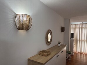 A modern interior with a wooden console table, a wall-mounted mirror, and a woven light fixture. - Vistamar Suite 158 (Tacoronte)