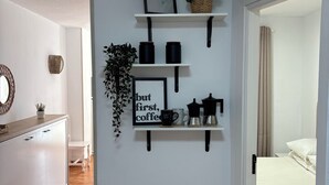 A modern interior with white walls, a wooden cabinet, and a coffee station with a sign. - The Vistamar Suite 154 (Tacoronte)