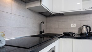 A modern kitchen with a black countertop, white cabinets, and a built-in stove.