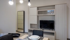 A modern dining area with a TV, seating, and a mirror.