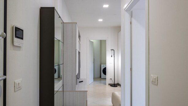A modern hallway with a built-in wardrobe, a washing machine, and a floor lamp.