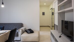 A modern living room with a sofa, a dining table, and a TV.