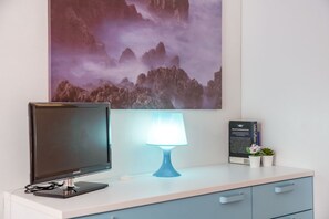 A desk with a computer monitor, a blue desk lamp, a framed informational poster, and a small potted plant. - Functional and comfortable apartment perfect for accommodating up to 3 guests is located in a strategic position, we are in the beating heart of the Riomaggiore village. The railway station, the port, the shuttles of the National Park, and the tracking p (Riomaggiore)