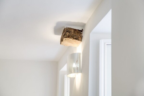 A ceiling with a wooden beam and a wall-mounted light fixture.