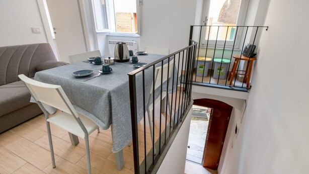 A dining area with a table set for four, a sofa, and a staircase leading to an upper level.