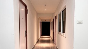 A long, narrow hallway with doors on both sides, leading to rooms. - Aowmana Hotel (Bangkok)