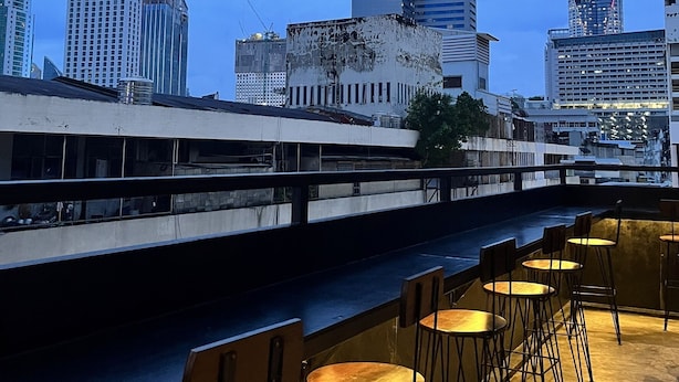 A rooftop bar with outdoor seating and a city skyline in the background. - Aowmana Hotel (Bangkok)