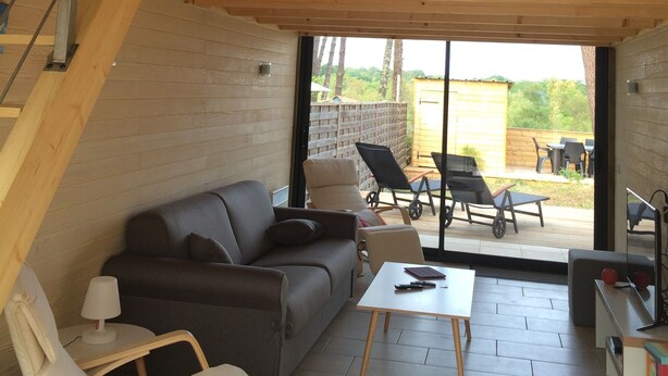 Ein moderner Loft-Wohnraum mit einer Holztreppe, einem Sofa, einem Couchtisch und Blick in den Garten.
