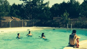 Ein Schwimmbecken mit drei Personen im Wasser und einer Person am Beckenrand.