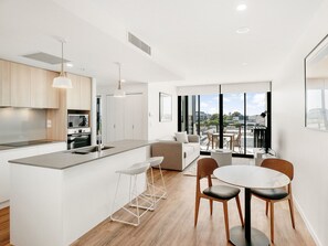 Una cocina moderna con una isla central, taburetes de bar y un comedor con una mesa redonda y sillas.
