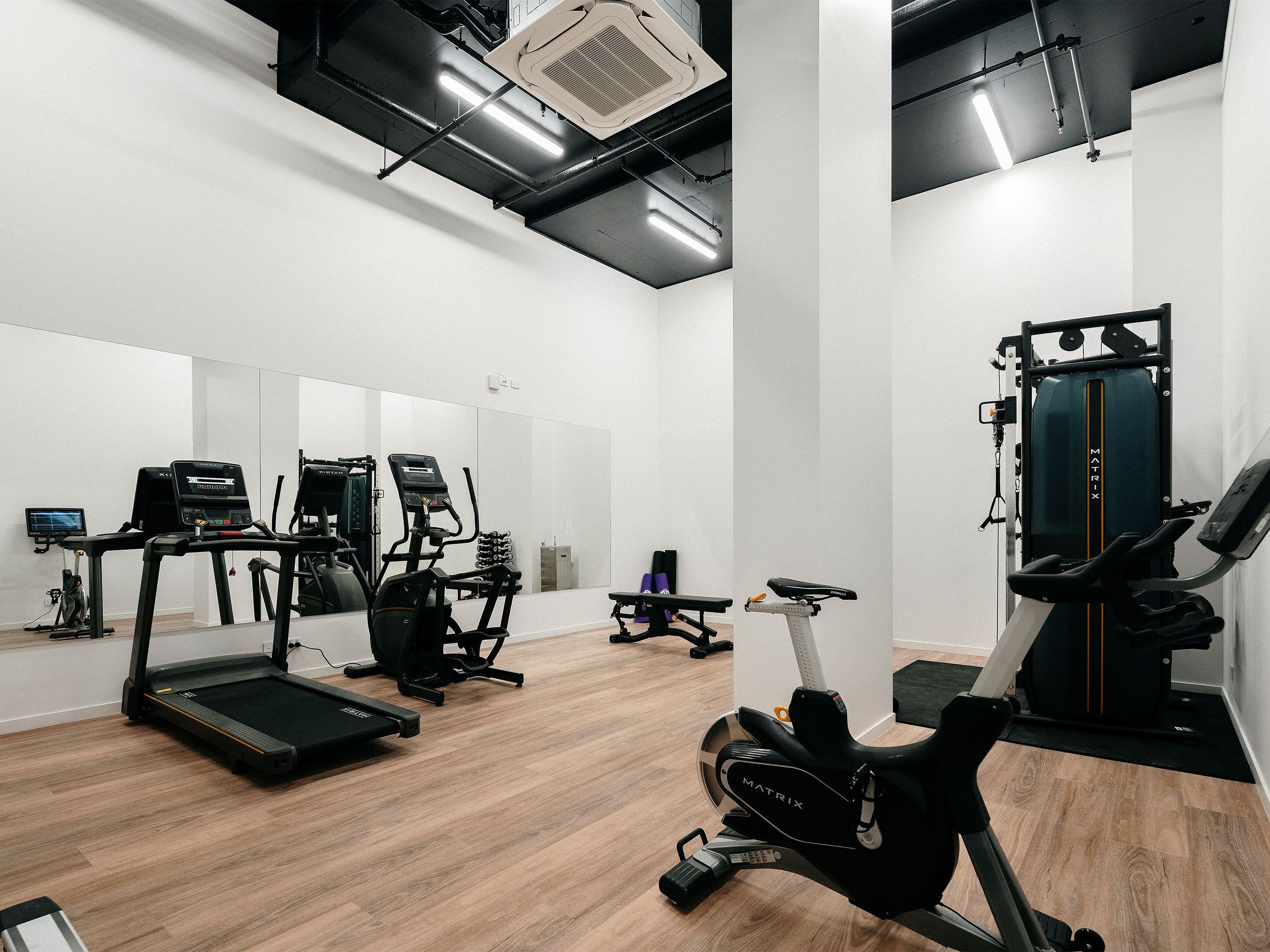 Une salle de sport équipée de tapis de course, de vélos elliptiques et d’un rameur.