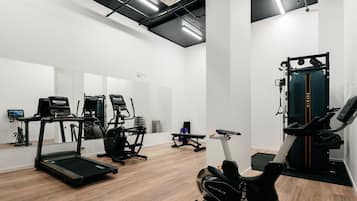 Une salle de sport équipée de tapis de course, de vélos elliptiques et d’un rameur.
