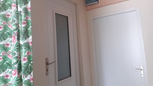 Una puerta blanca con un panel de vidrio satinado, un picaporte metálico y una cerradura.
