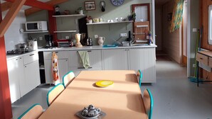 Una cocina compacta con comedor, que incluye un microondas, cocina y diferentes utensilios de cocina.