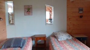 Una habitación pequeña y acogedora con dos camas, una mesita y una ventana.