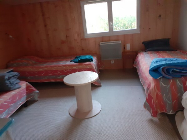 A room with two beds, a small round table, and a window.