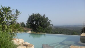 A clear infinity pool with a view of a forested landscape and distant hills. - Federico farmhouse with swimming pool and jacuzzi, panoramic position in Chianti (castellina in chianti)