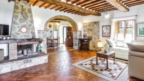 A spacious living area with a stone fireplace, wooden beams, and a tiled floor. - Federico farmhouse with swimming pool and jacuzzi, panoramic position in Chianti (castellina in chianti)