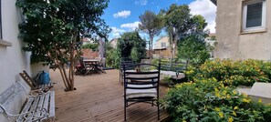 A wooden deck with outdoor furniture, surrounded by greenery and flowers.