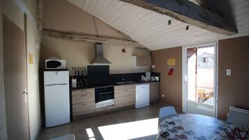 A compact kitchen with modern appliances, a dining area with a table, and a view through a door.