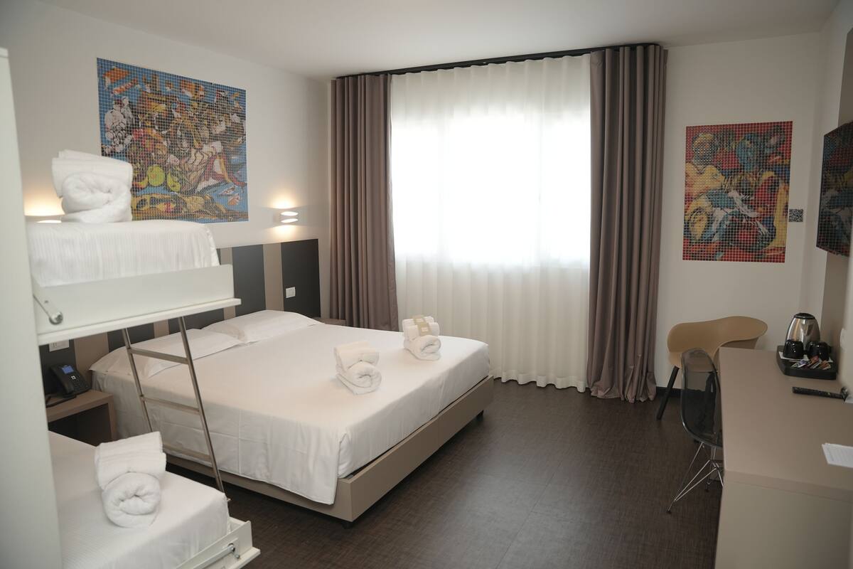 Ein Hotelzimmer mit Bett, Schreibtisch, Stuhl und Bildern an den Wänden.