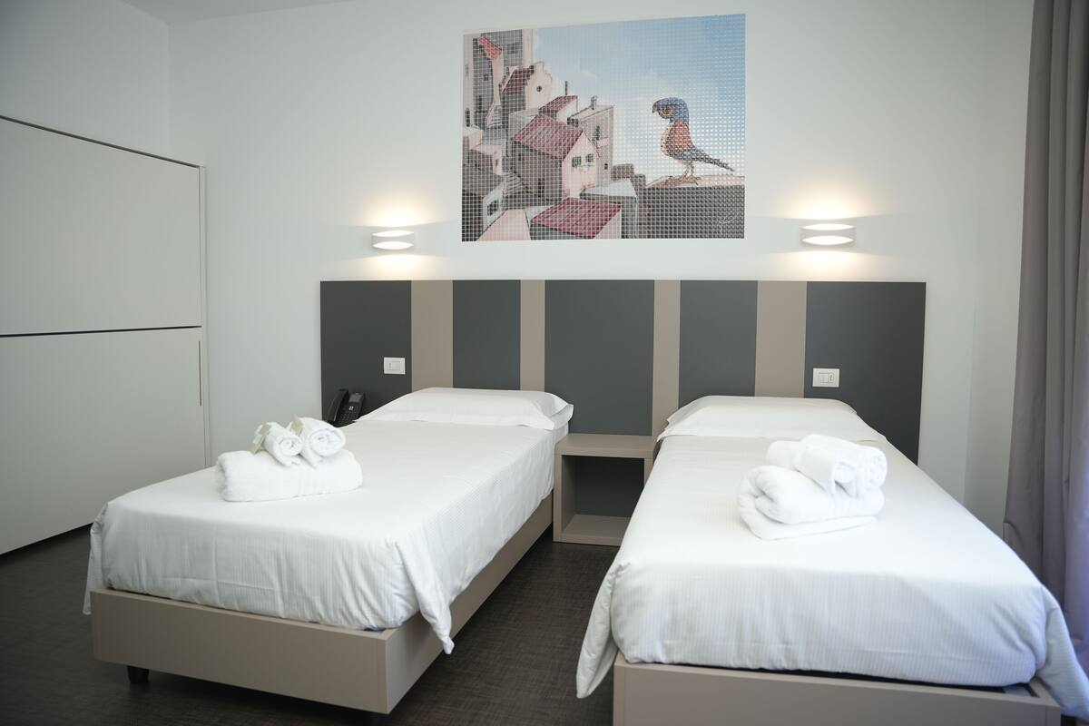 Ein Hotelzimmer mit zwei Einzelbetten, einem großen Gemälde darüber und einem modernen Design.