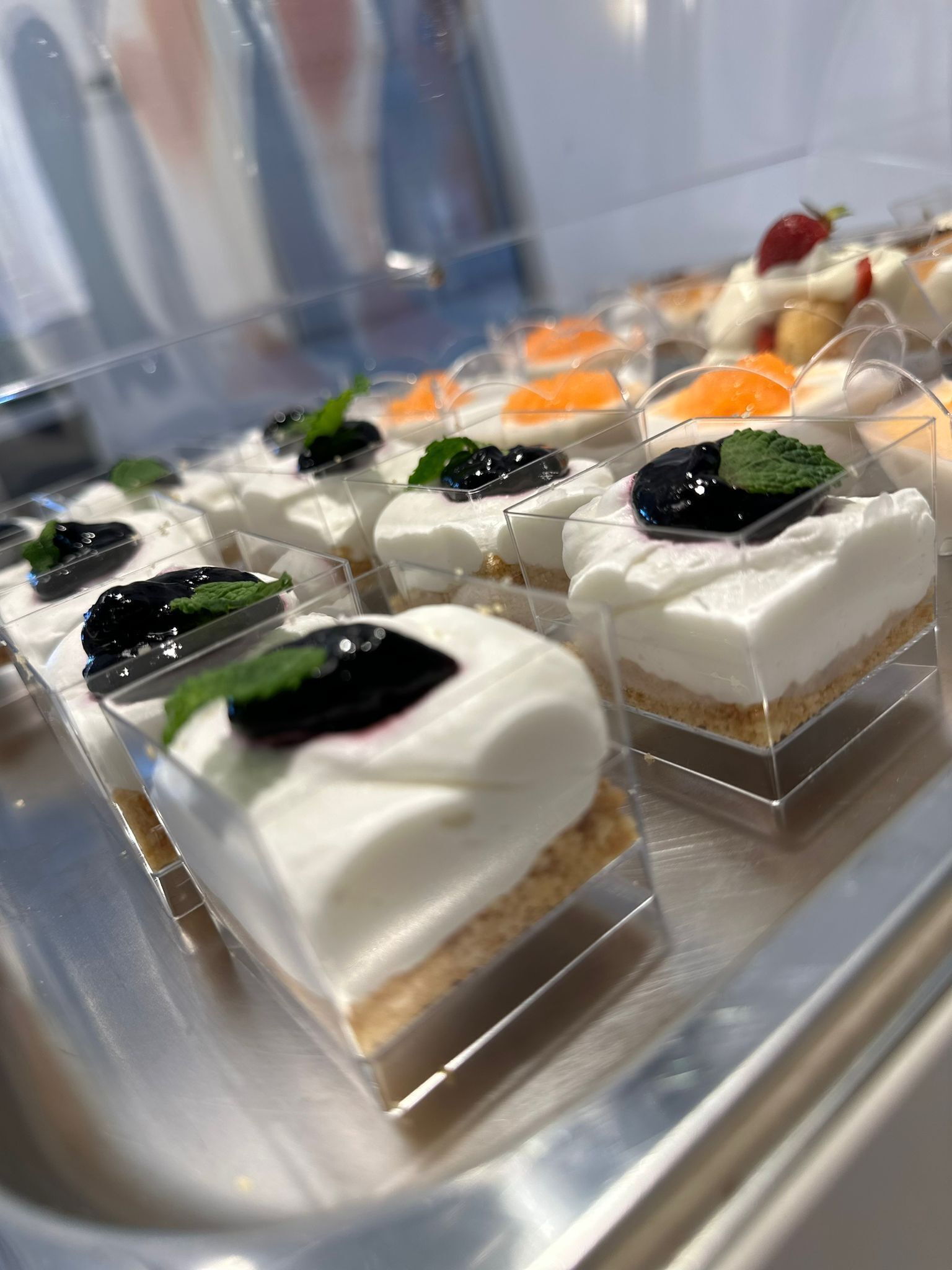 Verschiedene Desserts in durchsichtigen Behältern auf einer Platte.