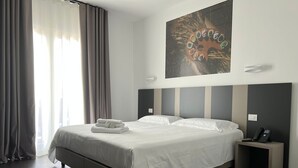 Habitación de hotel moderna con una cama grande, una mesita de noche con un teléfono y una obra de arte colgada en la pared.