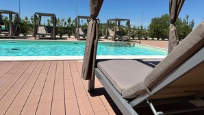 Zona de piscina con sillones de descanso y un área de estar techada.