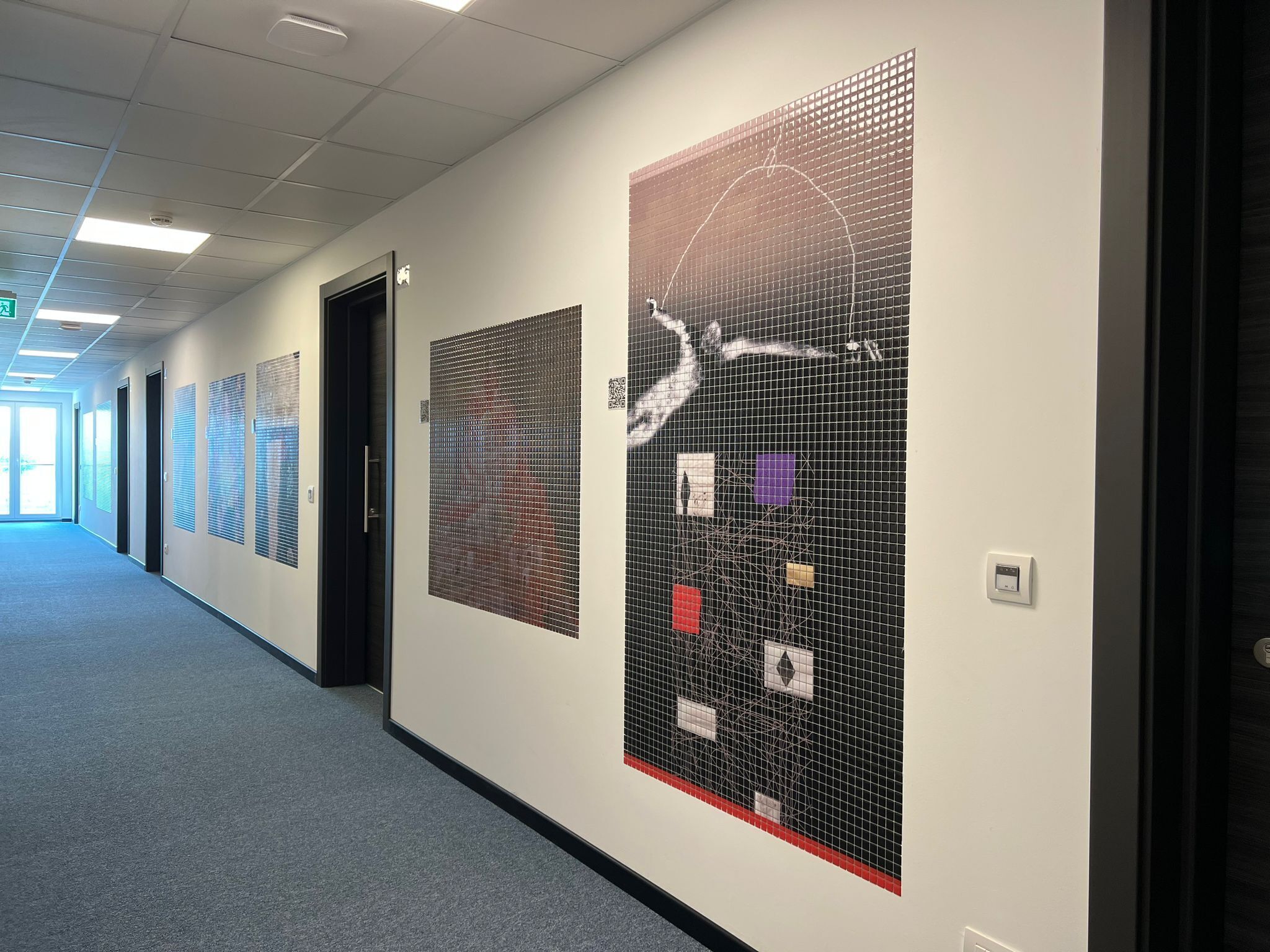 A hallway with doors, a wall with a grid pattern, and a ceiling with lights.
