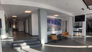 Un vestíbulo moderno con una escalera, dos zonas de estar y un gran mural.