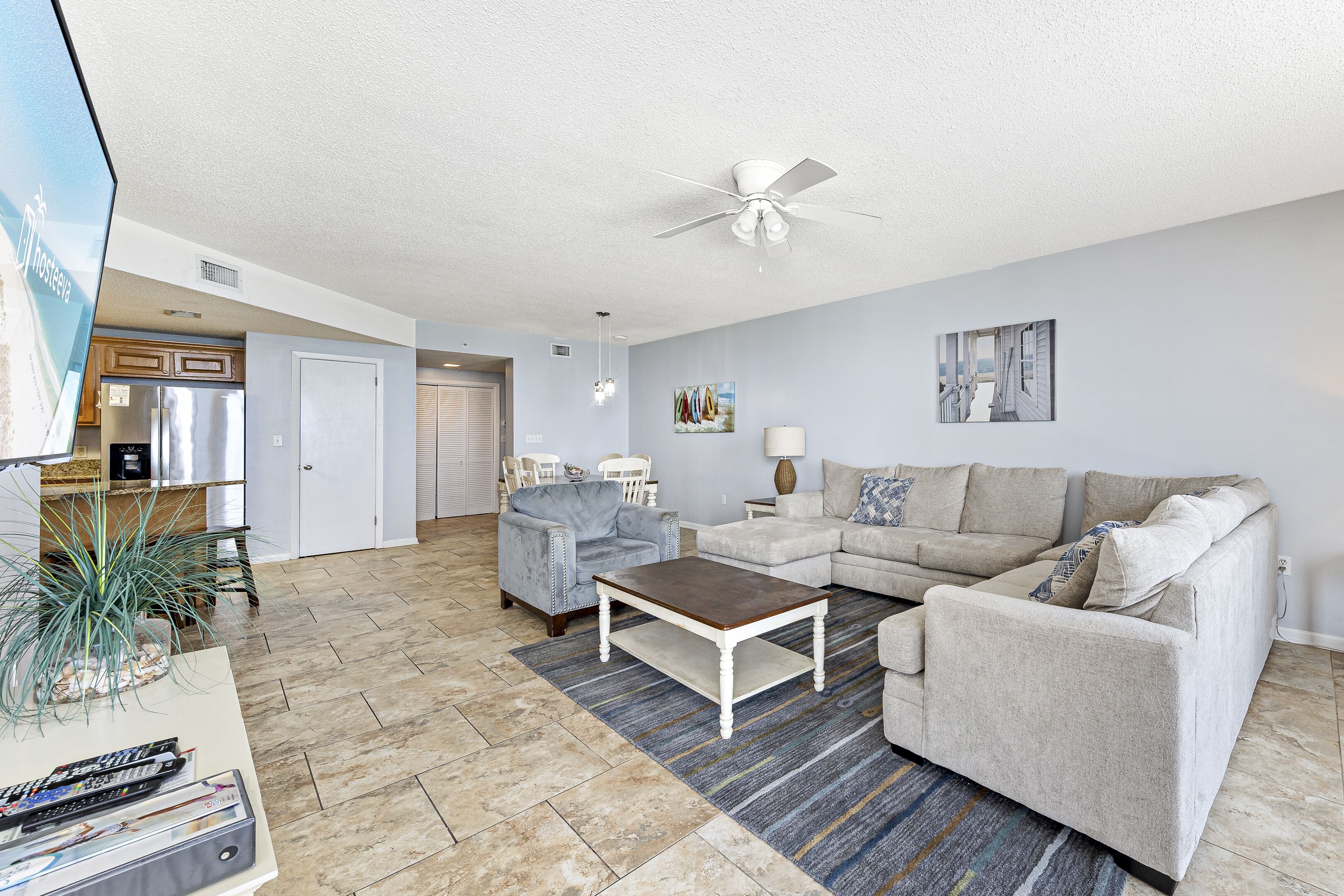 A spacious living room with a ceiling fan, a coffee table, a sofa, and a TV on a stand.