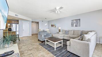 A spacious living room with a ceiling fan, a coffee table, a sofa, and a TV on a stand.