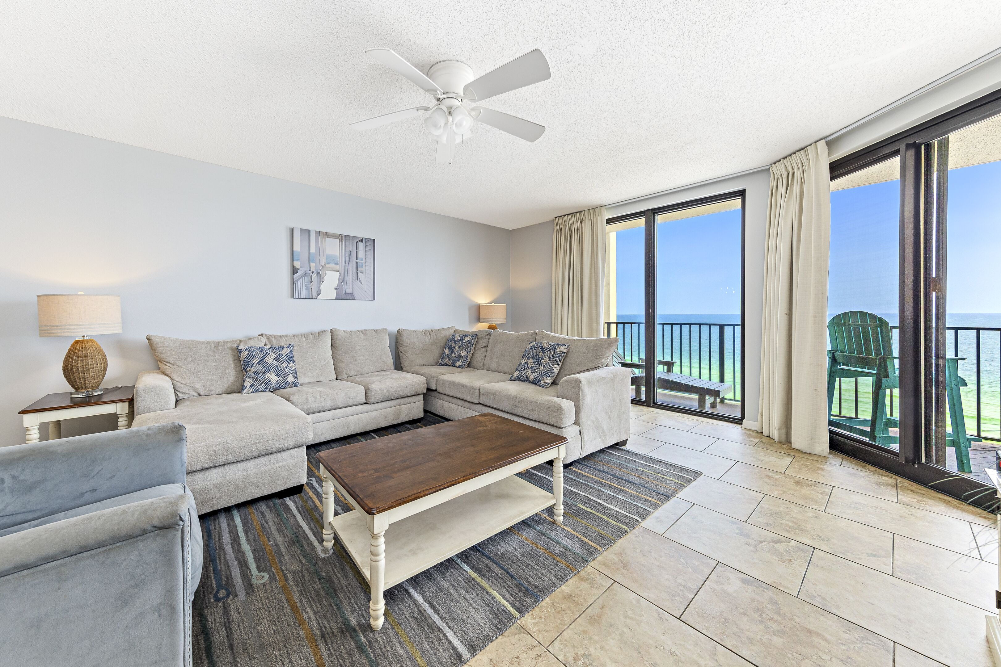 A living room with a sectional sofa, a coffee table, and a view of the ocean through large sliding glass doors.