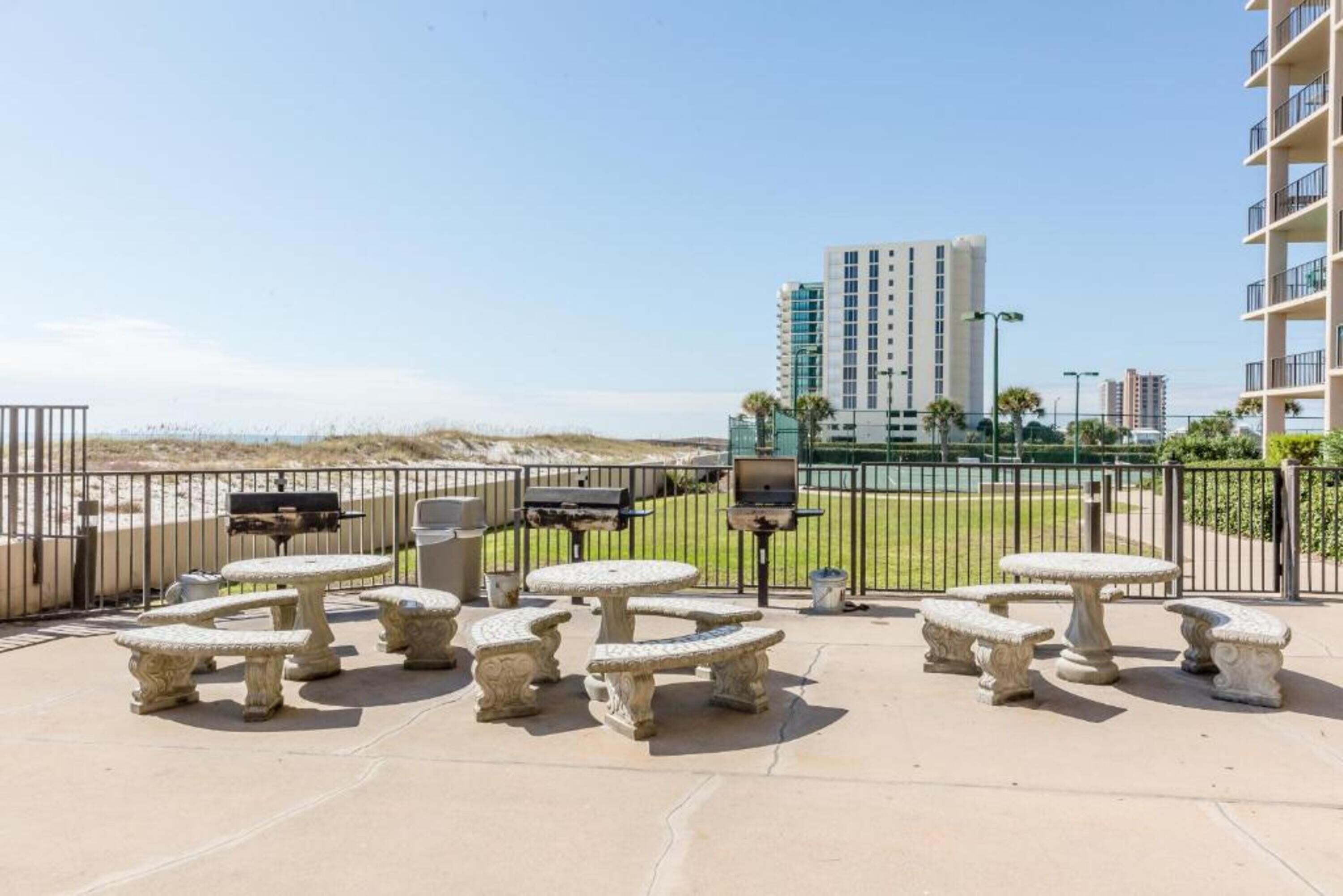 Mobiliario de patio exterior con vista a un edificio alto y una playa al fondo.