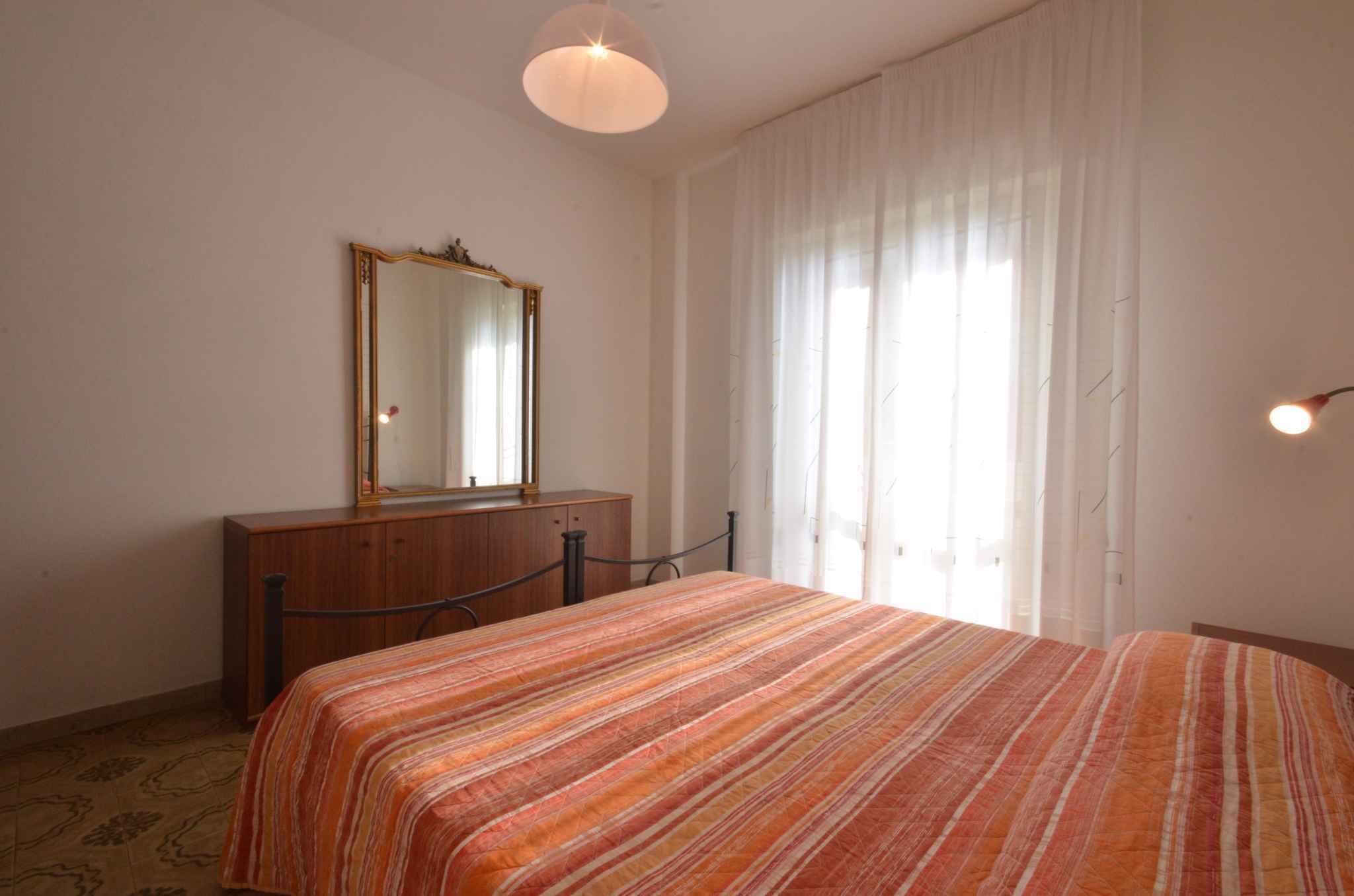 Un dormitorio con cama, cómoda, espejo y ventana con cortinas.