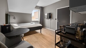 A modern room with a bed, a desk, a TV, and a kitchenette. - Forenom Serviced Apartments Drammen (Drammen)