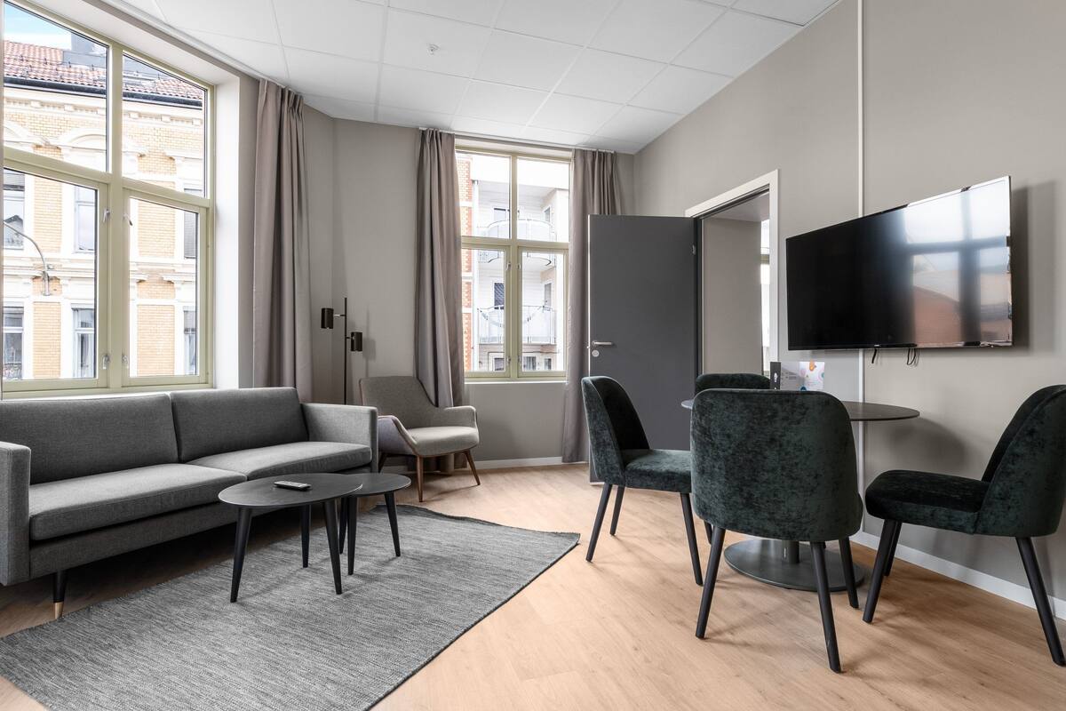 A modern living room with a sofa, chairs, a coffee table, and a TV.