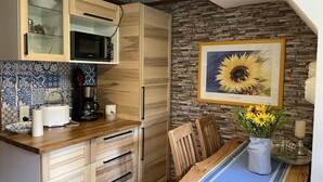 Eine Küche mit Holzausstattung, einer Mikrowelle, einer Kaffeemaschine und einem Esstisch mit Blumen in einer Vase.