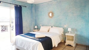 A bedroom with a bed, two bedside tables, a nightstand, a blue curtain, a white ceiling light, and a wall-mounted mirror. - Casa Juana, Adeje (Costa Adeje)