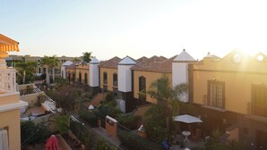 A courtyard with buildings, palm trees, and outdoor seating. - Casa Juana, Adeje (Costa Adeje)