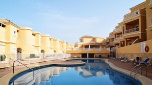 A swimming pool surrounded by yellow buildings with balconies and a white fence. - Casa Juana, Adeje (Costa Adeje)